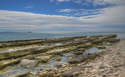rocky ground near sea under blue sky thumbnail