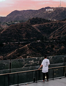 man standing on gray metal railings near Hollywood signage thumbnail