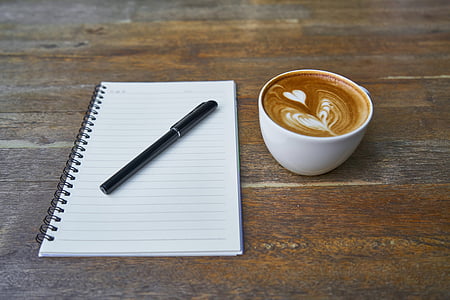 black pen on spiral notebook beside cappuccino art thumbnail