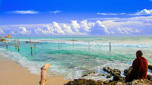 man sitting on rock formation near sea at daytime thumbnail