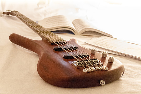 brown 5-strings bass guitar beside book thumbnail
