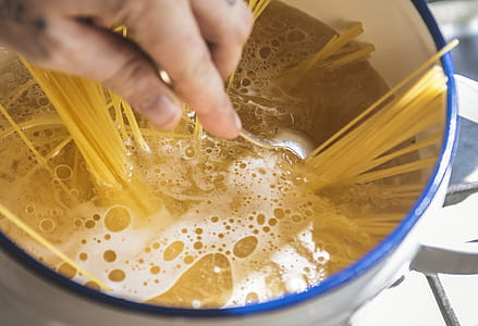 Person Holding Stainless Steel Spoon While Stirring Liquid Filled Casserole thumbnail