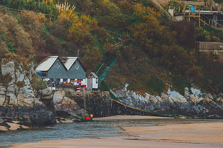 gray wooden house near shore during daytime thumbnail