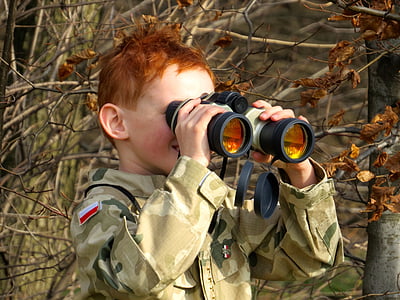 boy standing near twigs using binoculars thumbnail