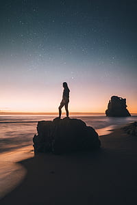 person standing on stone near body of water thumbnail