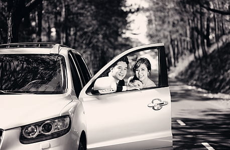 Man and Woman Behind Vehicle Door Grayscale Photo thumbnail