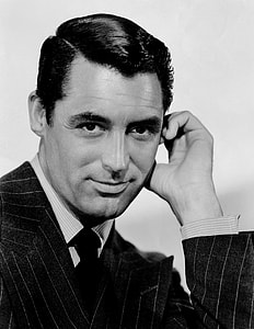 man wearing pinstripe suit with hand near left hand thumbnail