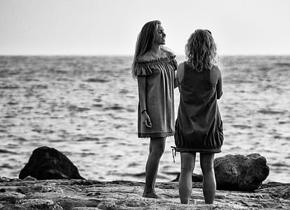grayscale of two women standing near body of water thumbnail