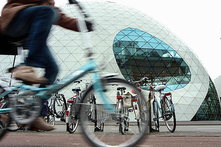 person riding bike passing by clear-glass dome building thumbnail