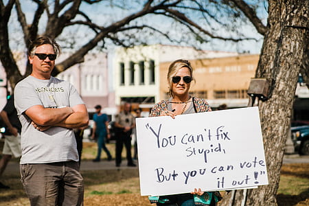 woman holding white and black signage thumbnail