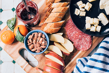 almonds, apples, bread, marmalade, orange fruits, and cheese on chopping board thumbnail