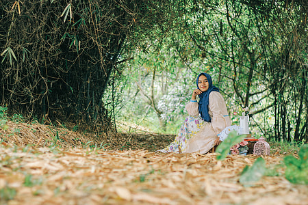woman lying on ground near trees thumbnail