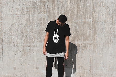 man looking down standing beside wall thumbnail