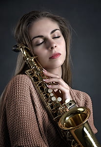 woman holding brass-colored saxophone thumbnail