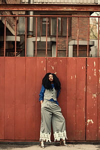 Woman Wearing Blue and Gray Outfit Standing Beside Gate thumbnail