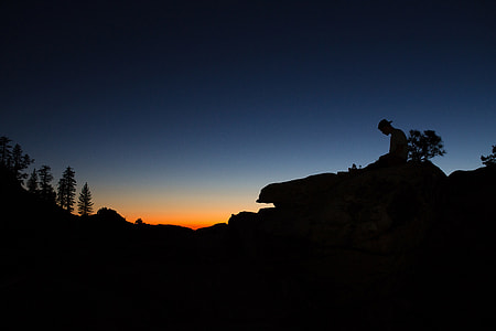 Silhouette of a man sitting on a rock at sunset in Yosemite Valley, USA thumbnail