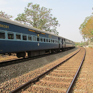 blue train on railway near trees at daytime thumbnail