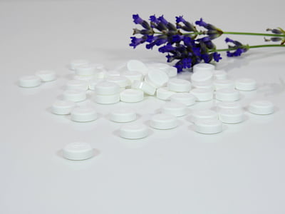 white medication pills and lavender flower on white surface thumbnail