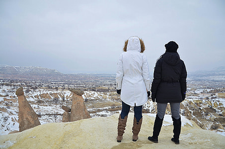 two person wearing black and white hooded jacket standing on rock formation during daytime thumbnail