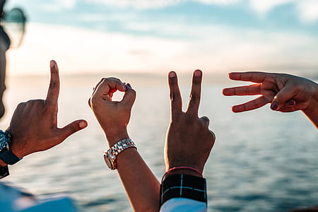person with watch facing body of water doing hand sign thumbnail