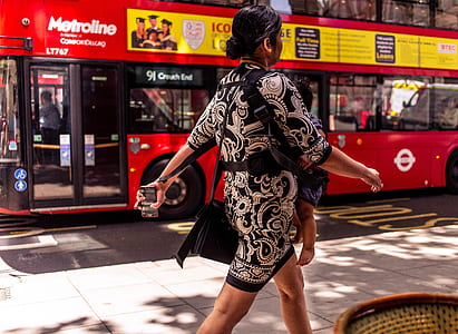 woman in black and white floral elbow-sleeved mini dress walking while carrying a baby at daytime thumbnail
