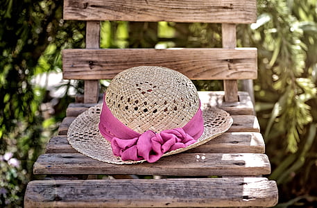 brown wicker hat with pink ribbon on top of brown wooden chair thumbnail
