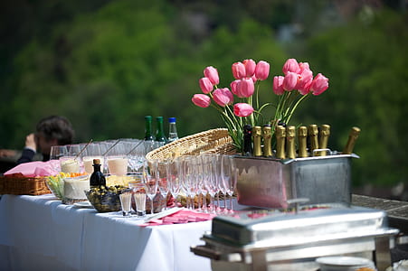 pink tulip flower arrangement beside wine glass and bottle on table thumbnail