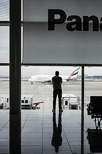 man standing on port watching Fly Emirates airplane during daytime thumbnail