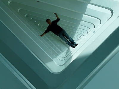 person wearing black elbow-sleeved shirt and blue denim jeans outfit standing on white concrete surface thumbnail