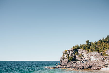 Young hikers on the rock near bay of turquoise blue ocean thumbnail