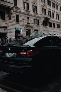 black BMW sedan parked on road side near building thumbnail