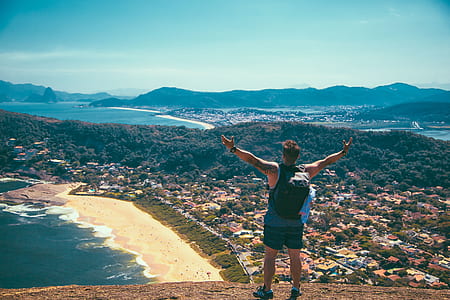 man standing on cliff near body of water thumbnail