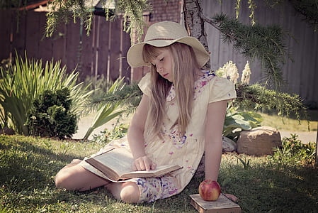 girl in yellow dress reading book sitting on green grass thumbnail