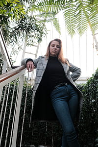 woman leaning on railing under green ferns thumbnail
