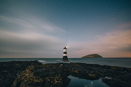 white and black light house near body of water thumbnail