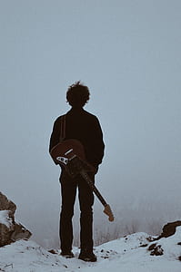 man standing on top of mountain wearing guitar thumbnail