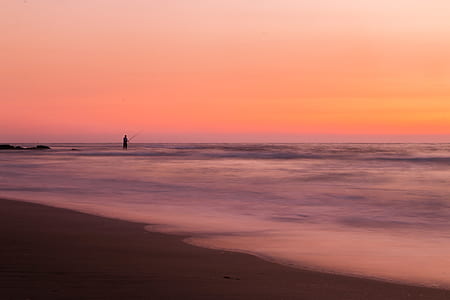 person standing on beach during sunrise thumbnail