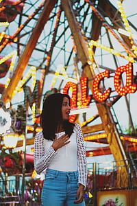 Woman Wearing Long Sleeve Shirt And Blue Denim Jeans Under A Ferris Wheel thumbnail