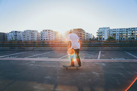 man wearing white t-shirt and black pants standing on skateboard during daytime thumbnail
