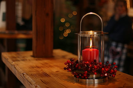 red lighted candle with flowers on wooden table thumbnail