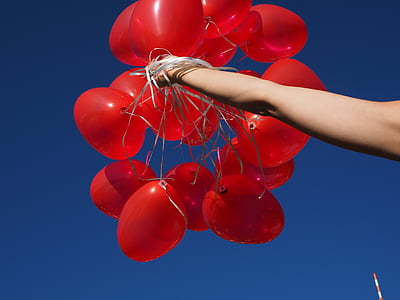 low angle photography of person holding bunch of red balloons thumbnail