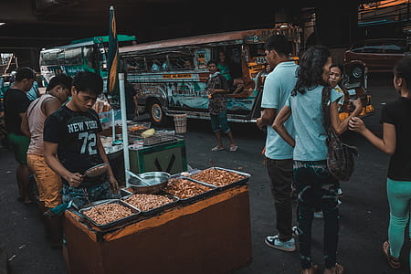 three vendors beside concrete road while group of people riding on vehicles thumbnail