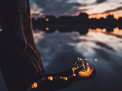 selective focus photography of woman holding string light thumbnail