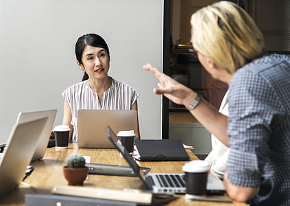 Men Talking to a Woman Sitting in Front of Silver Laptop Computer thumbnail
