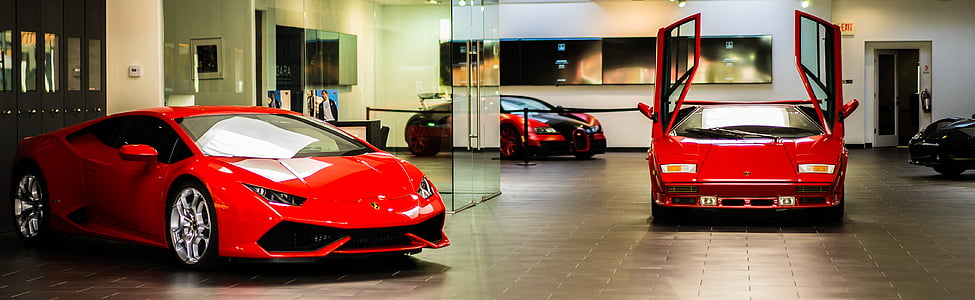 red Lamborghini Huracan and Lamborghini Countach sports coupes parked in garage thumbnail