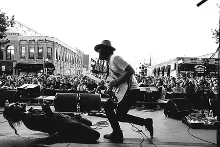 grayscale photography of two man playing guitars in front of crowd thumbnail