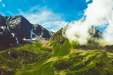 green mountain with smoke under blue sky thumbnail
