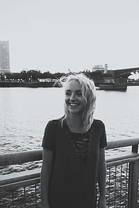 grayscale photo of woman standing near fence thumbnail
