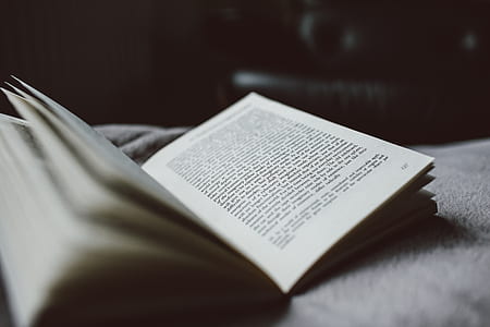 selective focus photography of book on white textile thumbnail