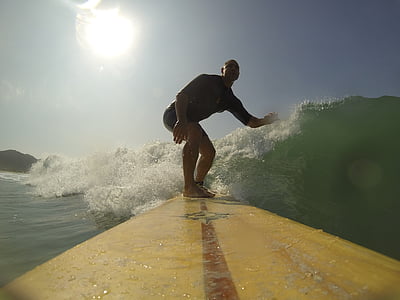 man riding on yellow surfboard while surfing on water waves thumbnail
